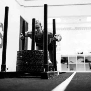 Woman pushing a weighted sled in a strength training session at TEAM NTS