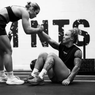 a woman helping another woman to lift her arm